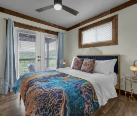Bedroom with ceiling fan and double glass doors to balcony in Tangier Aladdin-inspired cabin at Nature Mystique Retreat