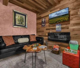 Living room with couch, electric fireplace, and TV in Daisy Hobbit-inspired cabin at Nature Mystique Retreat