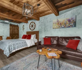 Couch and table with bed in background in Dalia Hobbit-inspired cabin at Nature Mystique Retreat