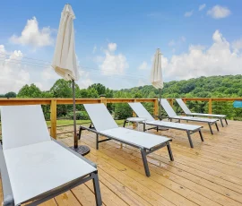 Lounge chairs on a deck overlooking the natural swimming hole at Nature Mystique Retreat