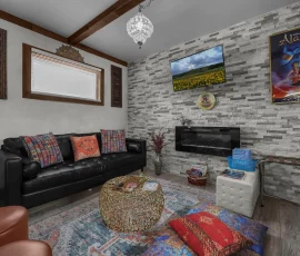 Living room with couch, electric fireplace, and TV in Marrakesh Aladdin-inspired cabin at Nature Mystique Retreat