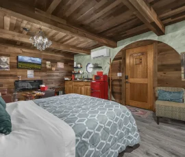 View of bed, front door, living room, and kitchenette in Forest Hobbit-inspired cabin at Nature Mystique Retreat