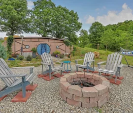 View of fire pit, hammock, and cedar hot tub with Aspen Hobbit-inspired cabin in the distance at Nature Mystique Retreat