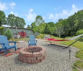 View of fire pit, hammock, and cedar hot tub with Dalia Hobbit-inspired cabin in the distance at Nature Mystique Retreat