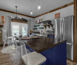 View of kitchen and island facing dining area and double glass doors to balcony in Tangier Aladdin-inspired cabin at Nature Mystique Retreat