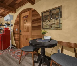 View of table with two chairs and kitchenette in background in Aspen Hobbit-inspired cabin at Nature Mystique Retreat