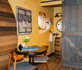 View of table and chairs with bathroom barn door slightly open in Aspen Hobbit-inspired cabin at Nature Mystique Retreat