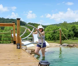 Woman entering the natural swimming hole at Nature Mystique Retreat