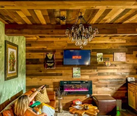Woman sitting on couch in Forest Hobbit-inspired cabin watching TV at Nature Mystique Retreat